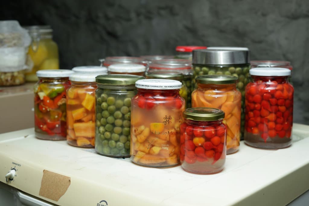Colorful fermented vegetable jars including tomatoes, peas, and peppers